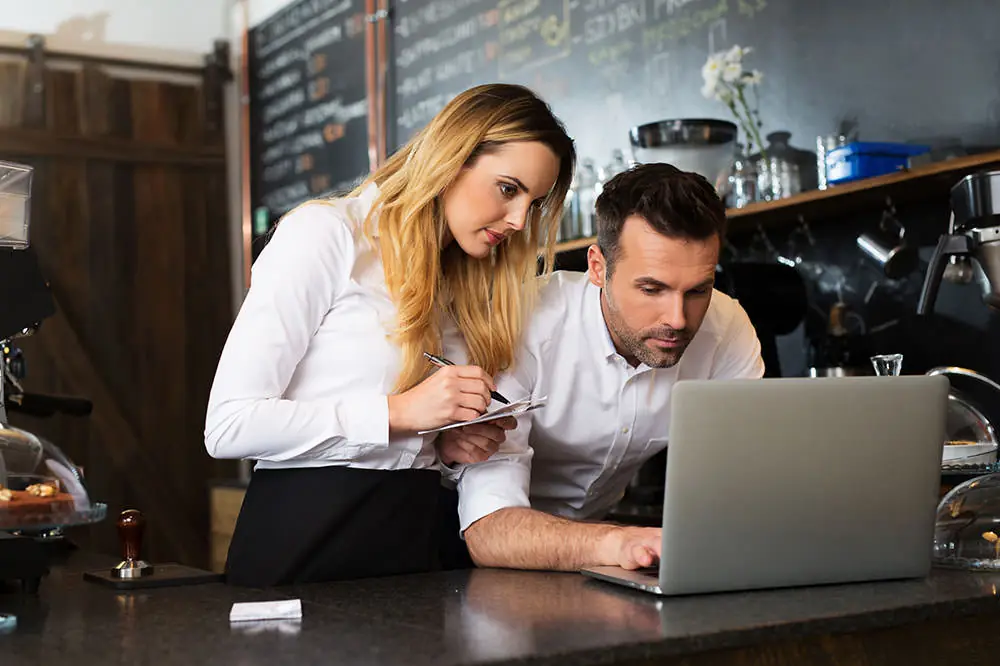 Two people going through paperwork together at a laptop